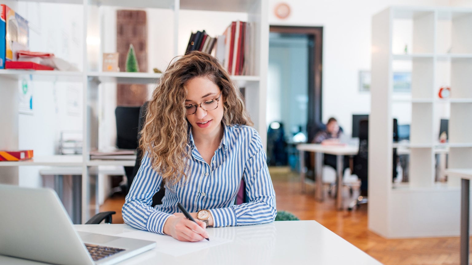 Female DrPH student taking notes for an assignment during her lunch break at work.