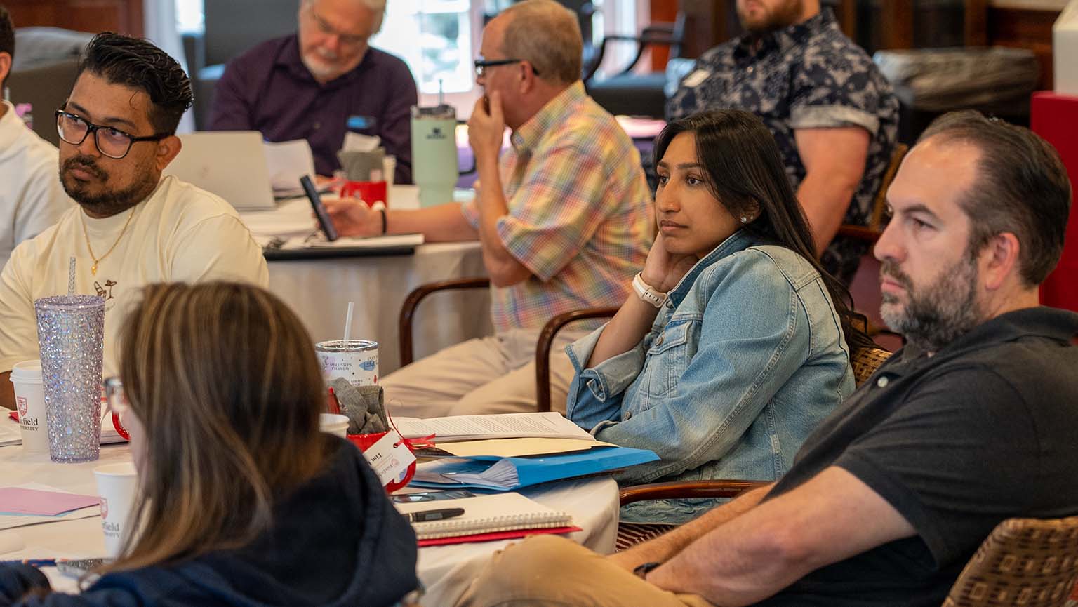 Several individuals sitting at a table, focused on their laptops, engaged in a group discussion or project.