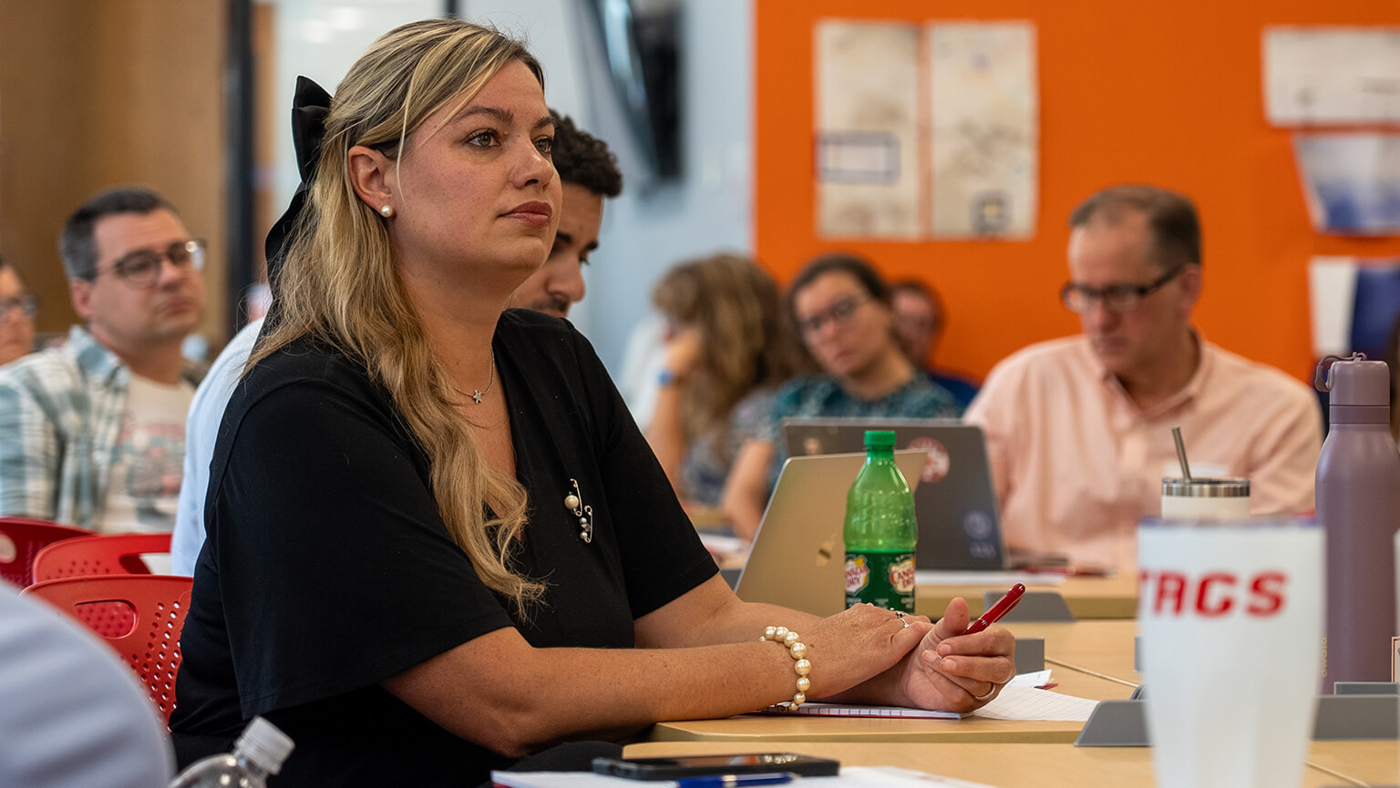 A woman seated at a table engaged in conversation with several other people around her.