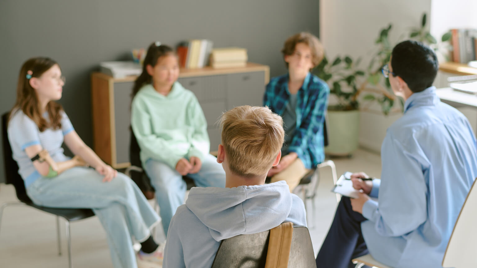 Social worker working with a group of adolescents in a private, intimate room setting.