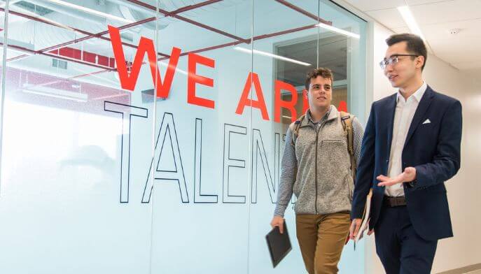 Two students walk down the hallway in the Business School. 