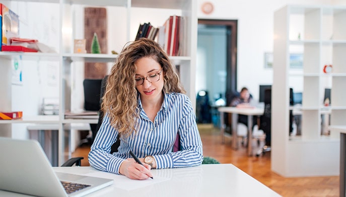 Female DrPH student taking notes for an assignment during her lunch break at work.