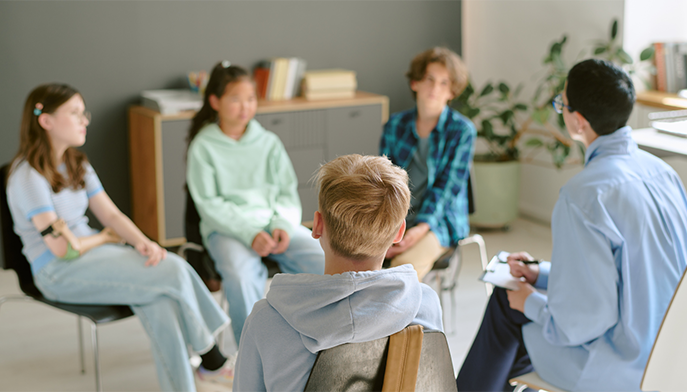 Social worker working with a group of adolescents in a private, intimate room setting.