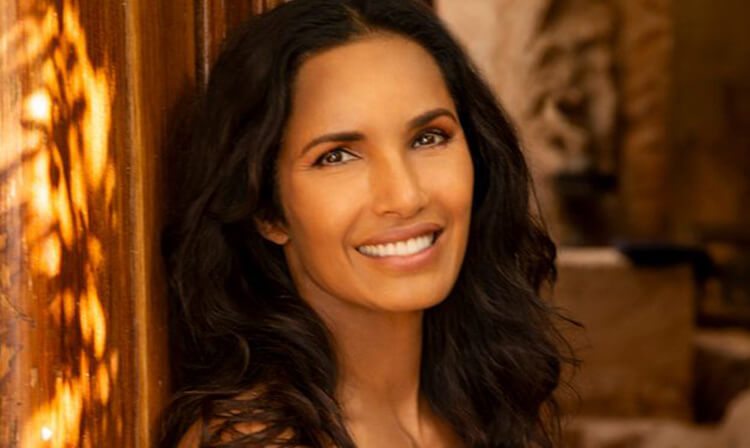 A woman with long black hair smiles warmly at the camera, exuding a friendly and approachable demeanor.