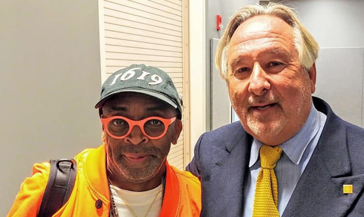 Two men dressed in orange and black jackets pose for a cheerful photo, showcasing their attire.  