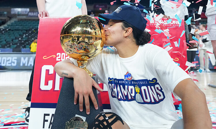 A woman passionately kisses a trophy on the court, symbolizing her hard-earned success and triumph.