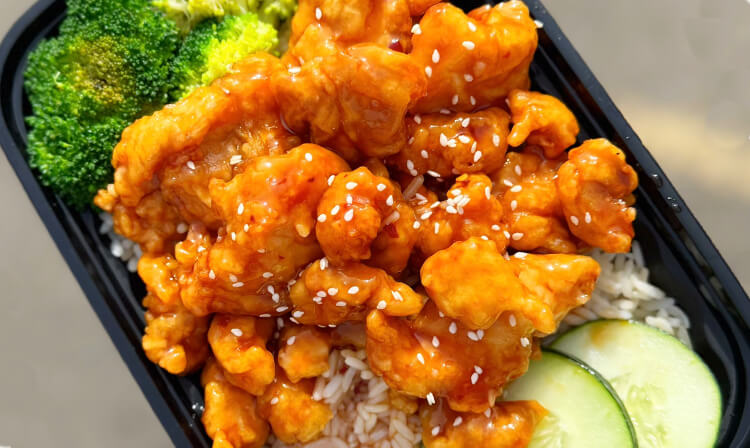 Chicken with rice and broccoli served in a black container, showcasing a balanced meal option.