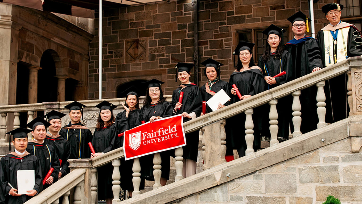 Graduates in caps and gowns stand on a staircase, showcasing their unity and joy on this momentous occasion.