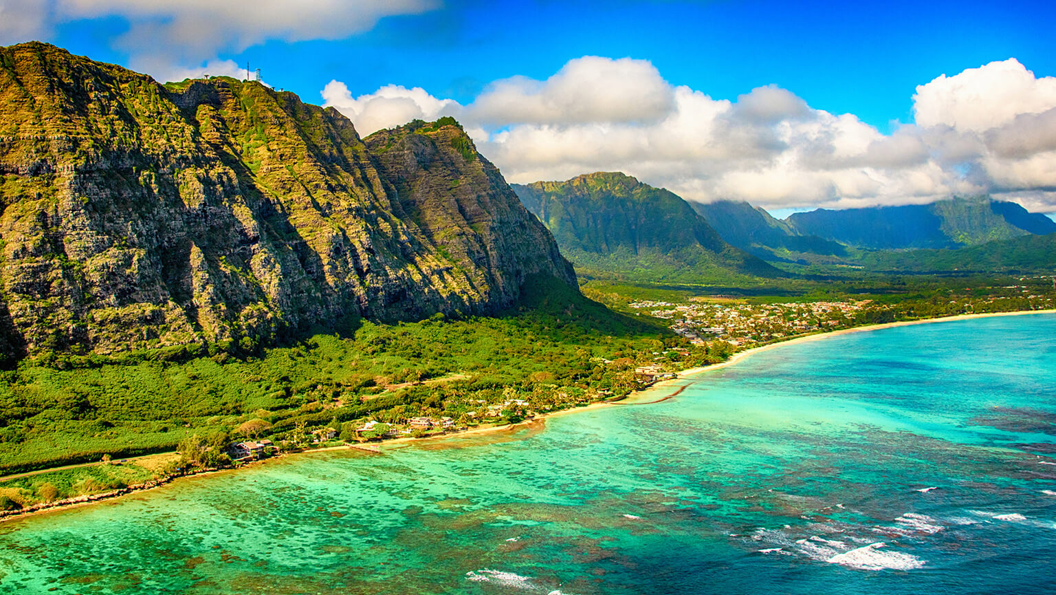 A picturesque scene of the northern shores of the Hawaiian island of Oahu surrounded by majestic mountains, highlighting the beauty of nature's landscape.