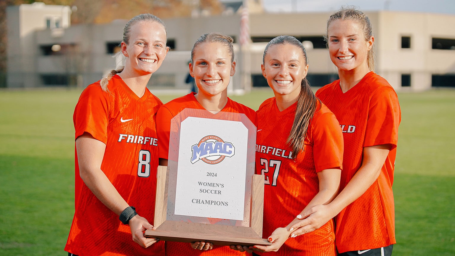 Four women's soccer athletes proudly holding up their 2024 Women's Soccer MAAC Champions plaque.