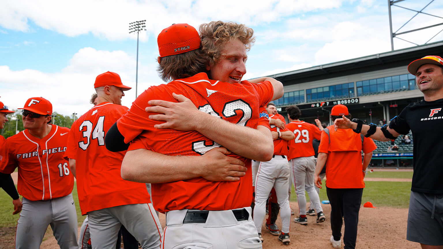 A group of baseball players joyfully hugging each other in celebration after a game. 