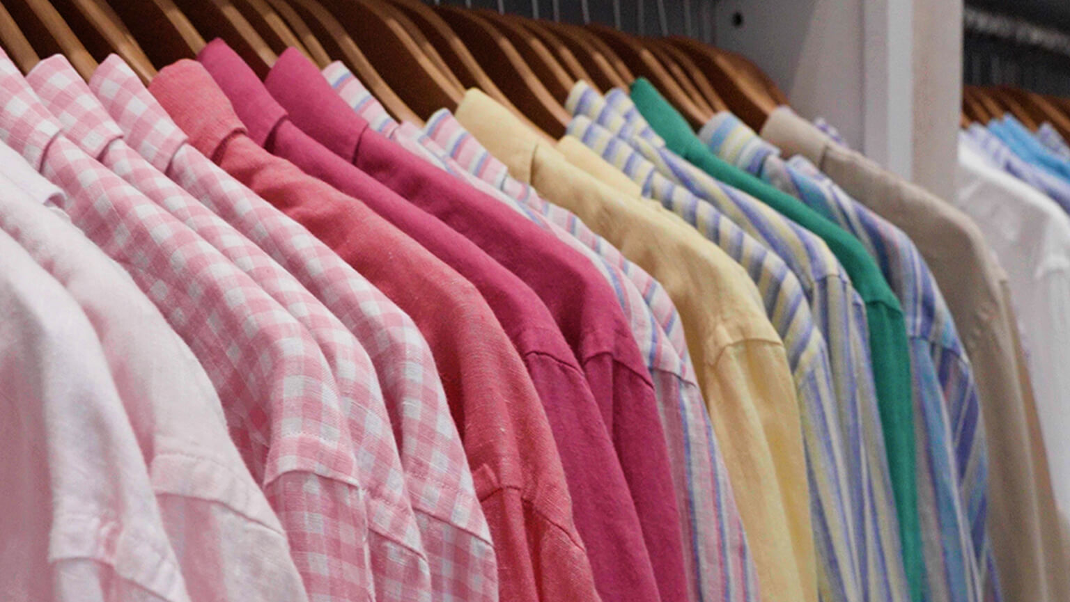 A colorful assortment of shirts displayed on a rack, showcasing a variety of hues