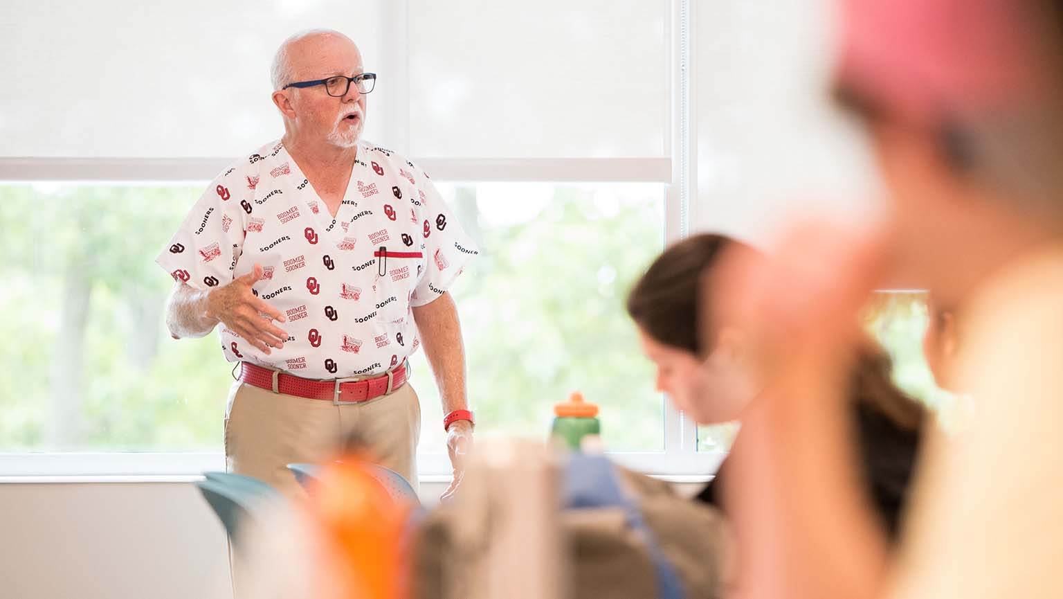 Image of  a man teaching in a classroom surrounded by attentive students.
