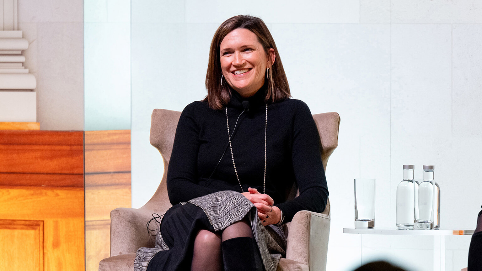 A smiling woman seated in a chair, actively participating in a discussion.