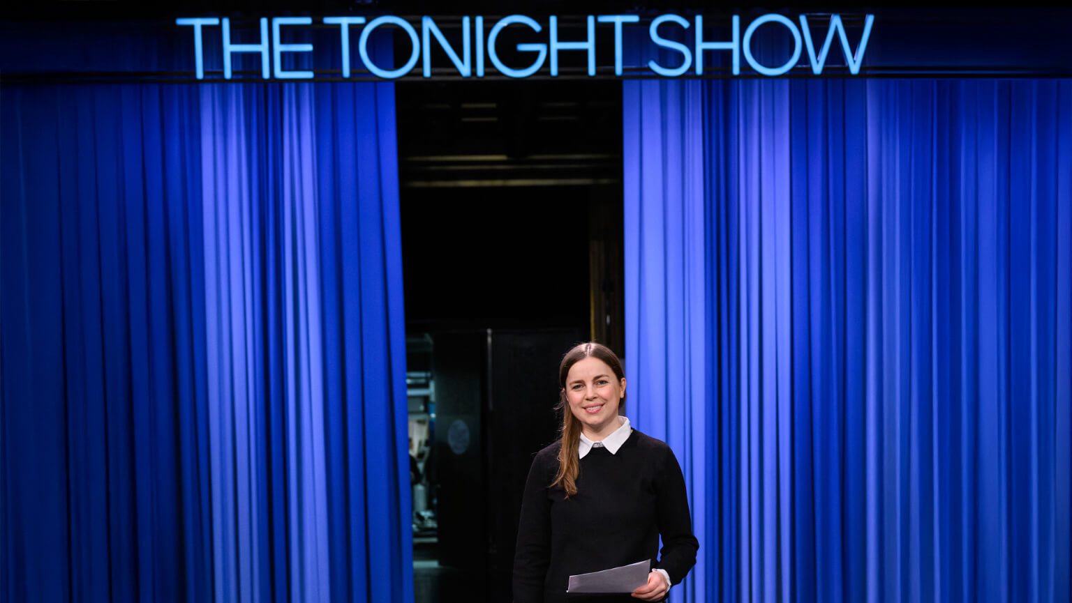 Image of "The Tonight Show" set featuring a student in front of blue curtain.