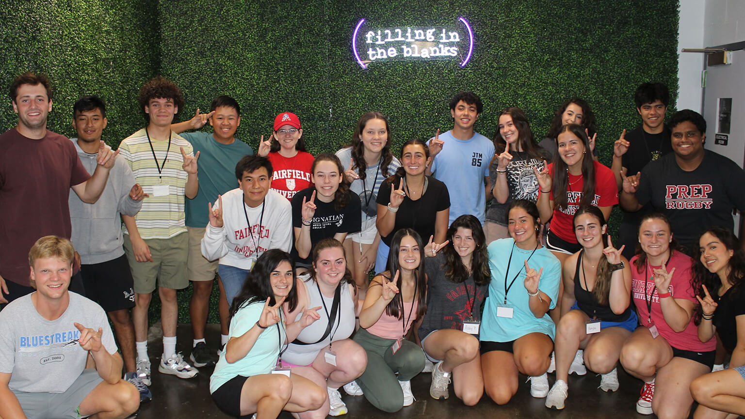 a group of students standing together, smiling for a photo in front of a textured wall.
