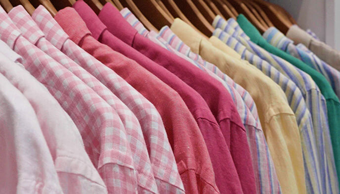 A colorful assortment of shirts displayed on a rack, showcasing a variety of hues