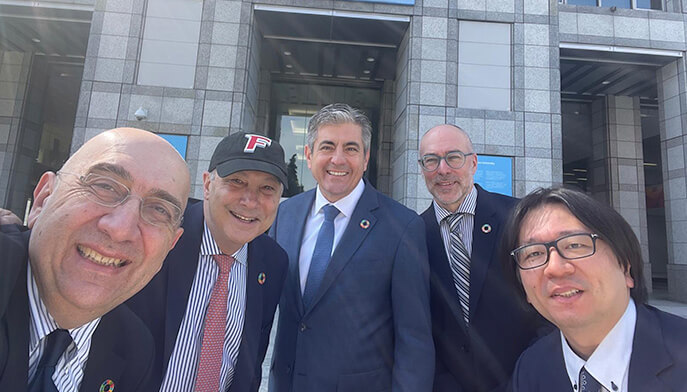 A group of four men dressed in suits and ties take a cheerful selfie together.