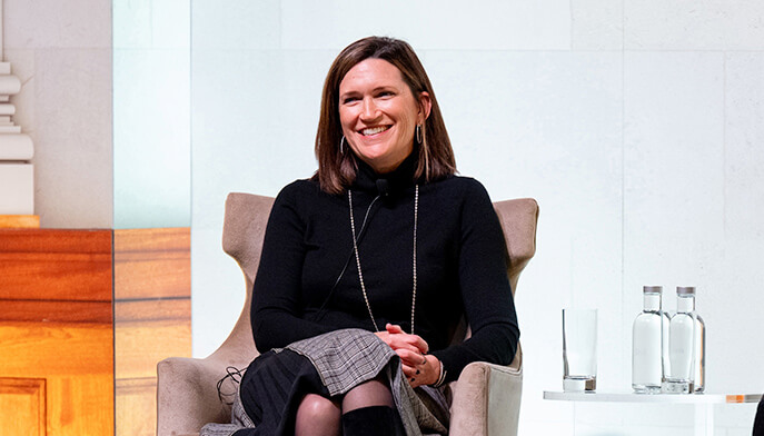 A smiling woman seated in a chair, actively participating in a discussion.