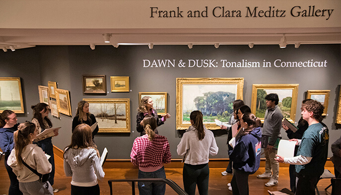 Visitors admiring paintings in the Fairfield University Art Museum, showcasing a variety of artistic styles and expressions.
