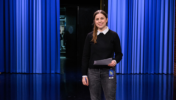 Image of "The Tonight Show" set featuring a student in front of blue curtain.