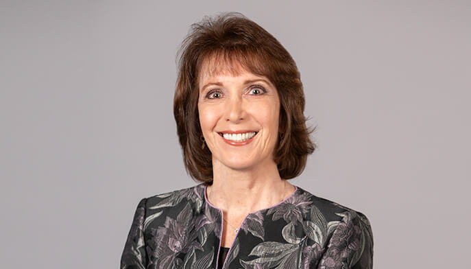 Headshot of Patricia Simino Boyce standing in front of beige background.