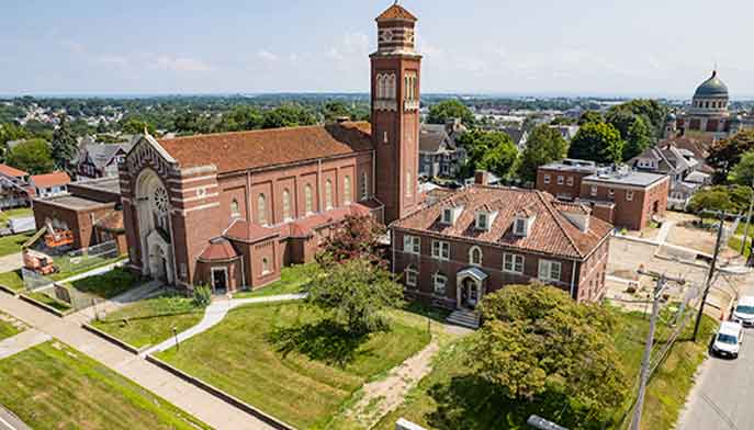 Aerial view of a church featuring a prominent steeple against a clear sky.