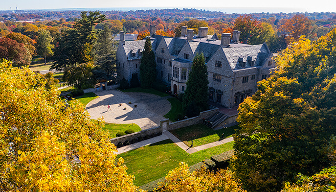 A substantial structure, Bellarmine Hall at Fairfield University campus is enveloped by trees, blending architecture with nature in a tranquil setting. 
