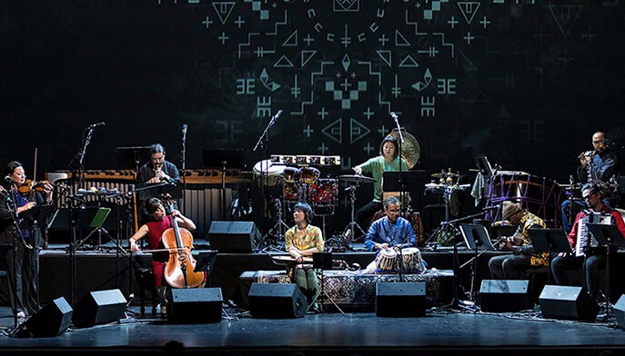 A group of musicians performing on stage, each playing various instruments in a lively concert setting.