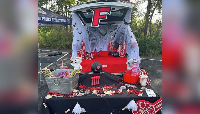 A table covered with Halloween decorations on a red and black tablecloth featuring a stuffed animal on top. 