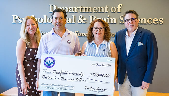 Four individuals pose with a $100,000 check in front of a sign for the Department of Psychological and Brain Sciences.