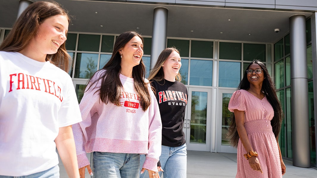 Four female students walking and talking together on their way to class.