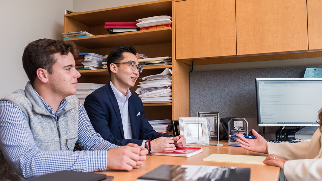 Two finance students meeting with a professor during her office hours to go over a project.