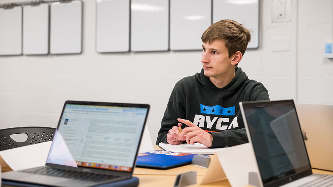 Financial technology student sitting in a study room with a fellow classmate as they collaborate on a project.