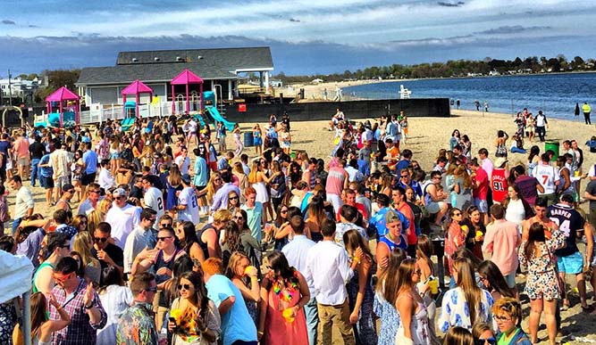A crowd of people stand on a beach.