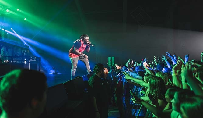 A performer sings on the left while the crowd stands on the right.