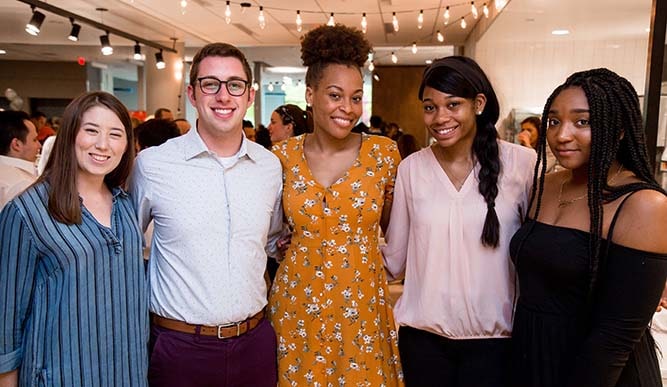 Four students in formal attire pose for a photo.