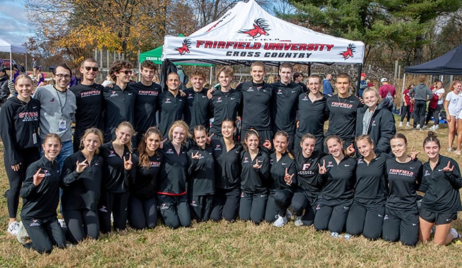 Women's cross country student-athletes posing and smiling as a group at a campus sports fair.