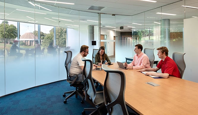Business students collaborating on a project at a meeting table in the Dolan School of Business building.