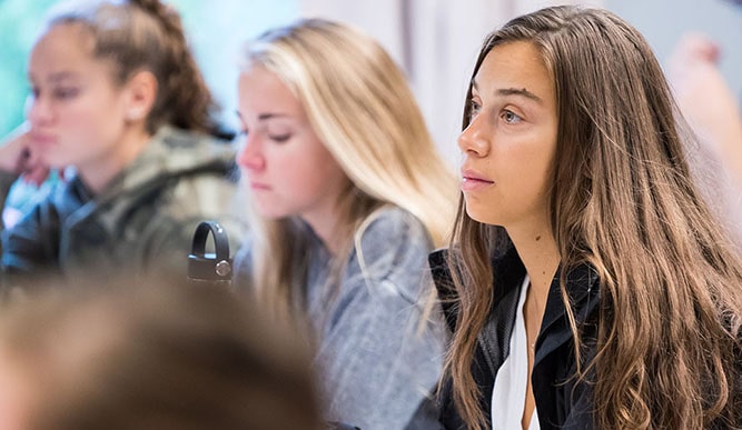 A classroom scene featuring a group of girls seated at desks, participating in a collaborative learning environment.