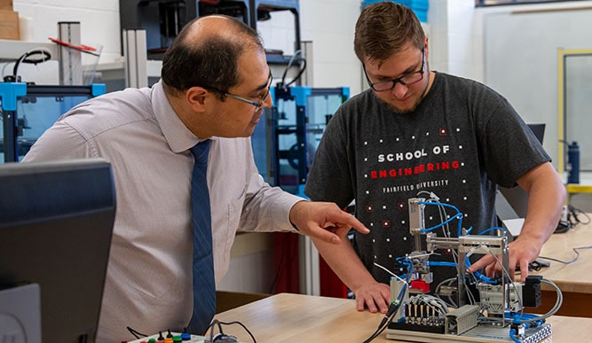 Professor and engineering student working together on programming an interactive piece of hardware.