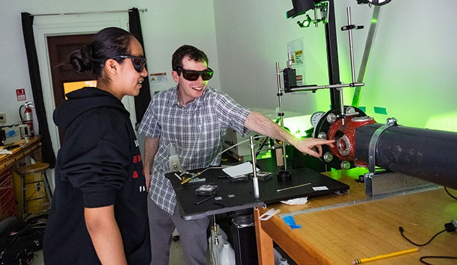 Students wearing protective eyewear as they work with a green laser system.