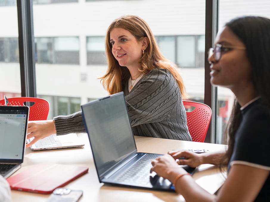 Fairfield Dolan students sitting in a study room together while they draft write-ups for their internship experience.