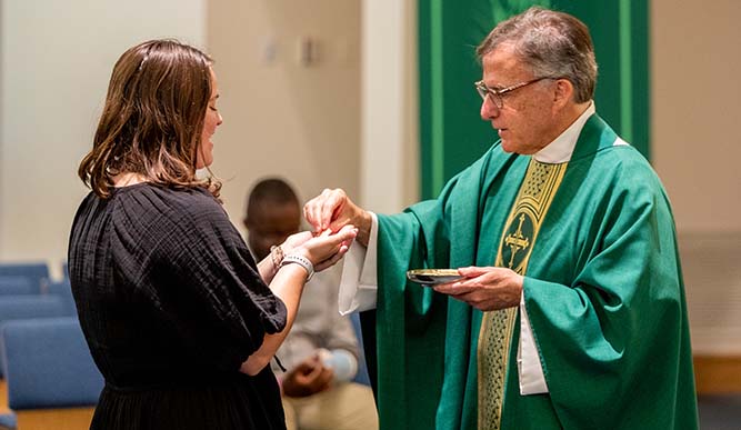 A woman receives communion from a priest in a church