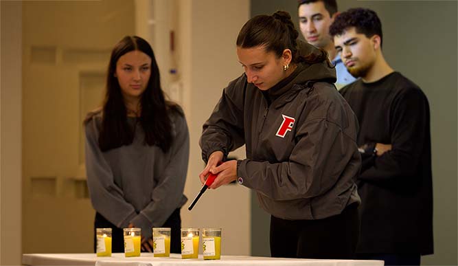 A woman stands beside a table featuring glowing candles