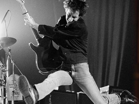 Photo of Pete Townshend of The Who leaps in the air while performing live on stage