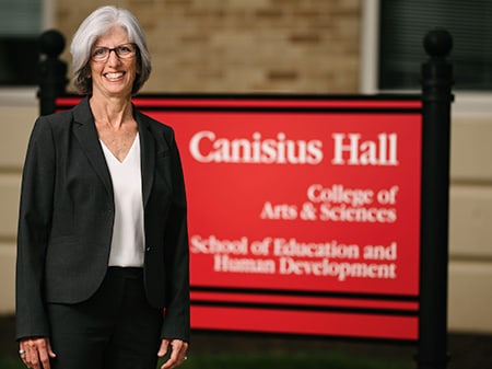 Dean Grupp standing and smiling in front of a Canisius Hall sign.