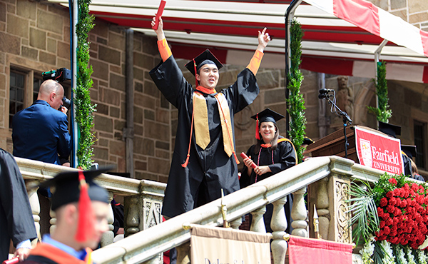 Photo of a student graduating on the back of Bellarmine Hall