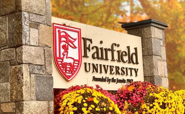 Colorful Fall shot of the Fairfield University entrance sign adorned with flower bushes.