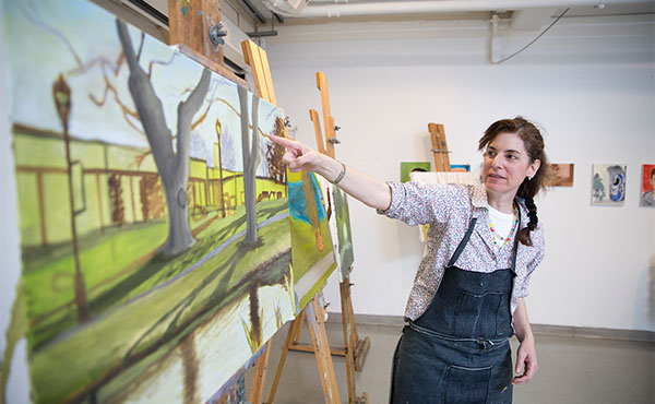 Image of Suzanne Chamlin-Richer, MFA, associate professor in the studio art program pointing to a painting.